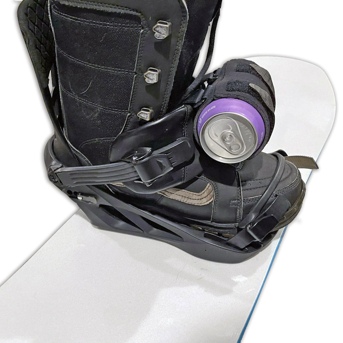 Studio close-up of the black beer can holder strapped to a snowboard binding's front strap, holding a can.