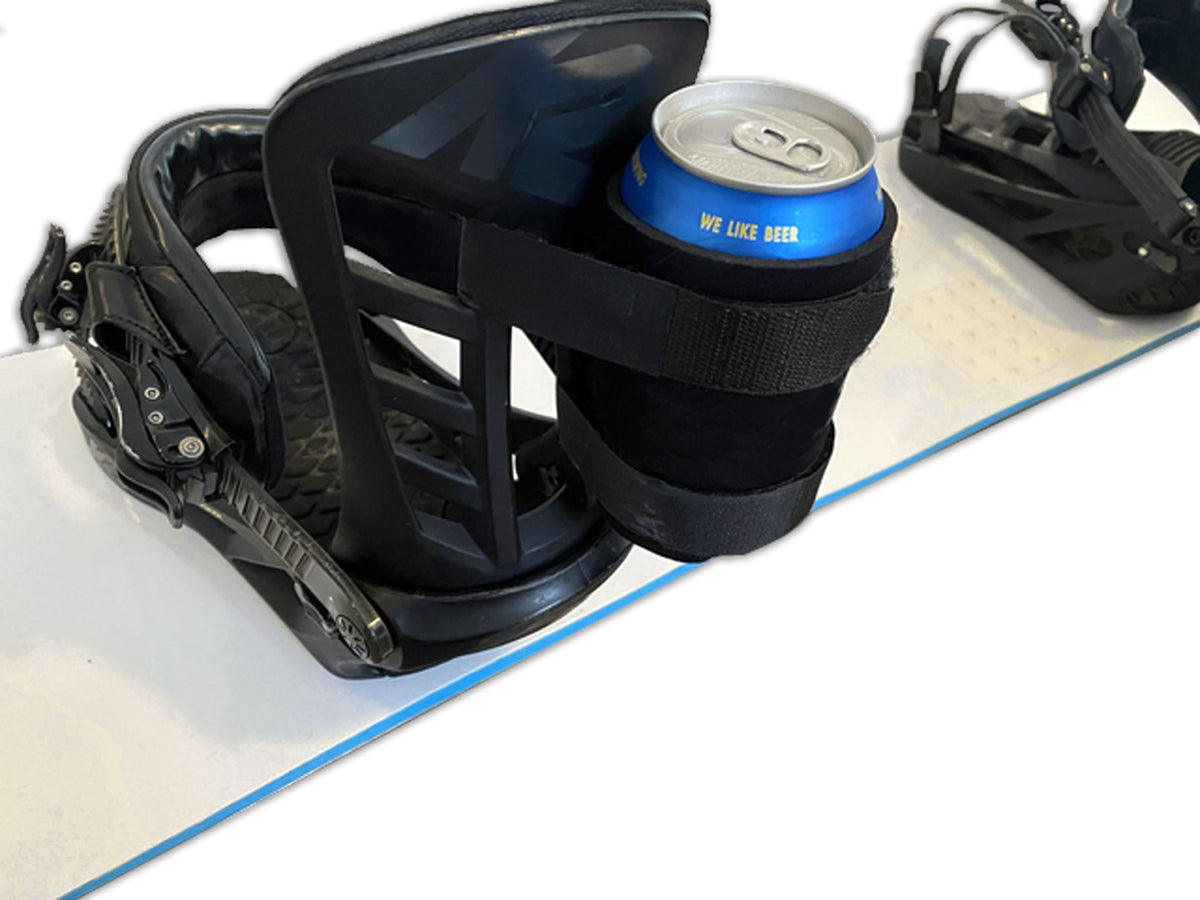 Black beer can holder strapped to a snowboard binding, holding a blue can on a snowboard.